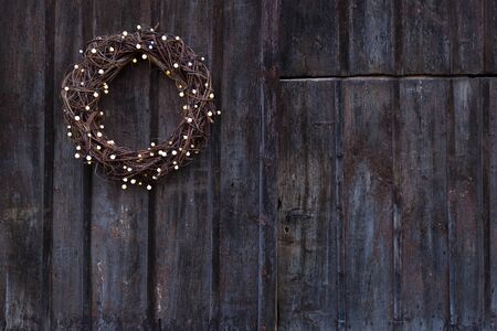 Advent wreath  with little light bulbs hanging on an old rough wooden doorの写真素材