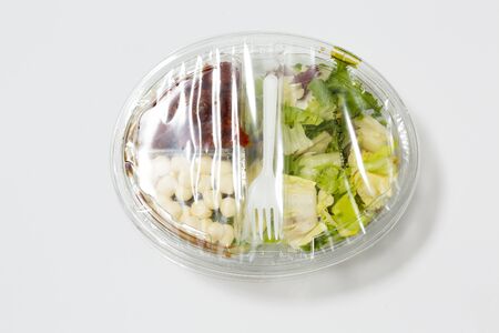 Use less plastic! Food in plastic packaging isolated on white ground. Symbol for environmental pollution done by the food industryの写真素材