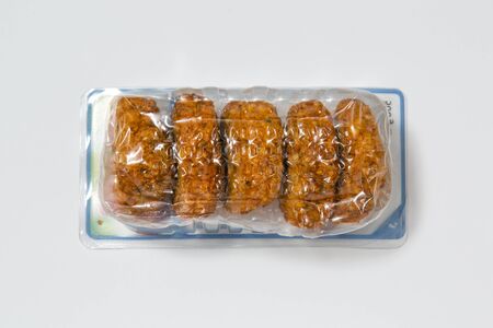Use less plastic! Food in plastic packaging isolated on white ground. Symbol for environmental pollution done by the food industryの写真素材