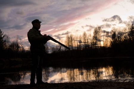 Silhouette of the hunter on a background of a morning dawnの写真素材