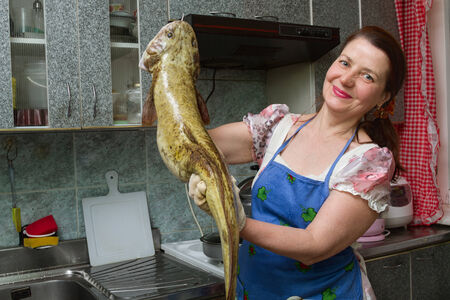 woman on kitchen with the big fishの写真素材