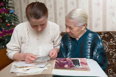 two women consider old photos in which they are represented at young age