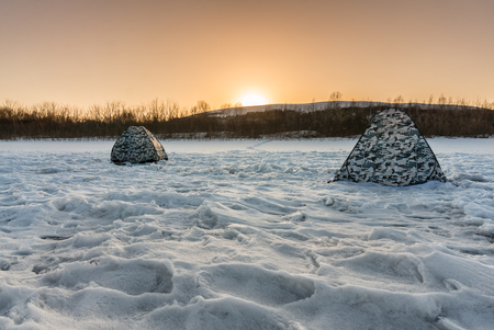 Winter fishing on the river in the evening at sunsetの写真素材