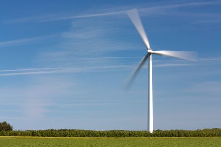 Windmill with rotating wings against a clear blue skyの写真素材