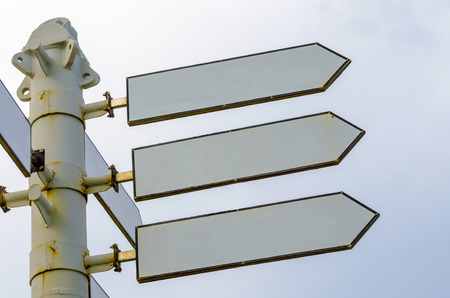 An image of arrow sign pole lacated on the road near the sea in sunset timeの写真素材