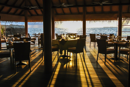 In image of wonderful sun light and shadow on the wooden floor of restaurant which have blue sea and blue sky as back groundの写真素材