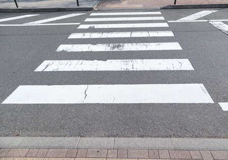 Zebra crossing trespassing with some faded on asphalt road.Background for safety first or transportation concept.の写真素材