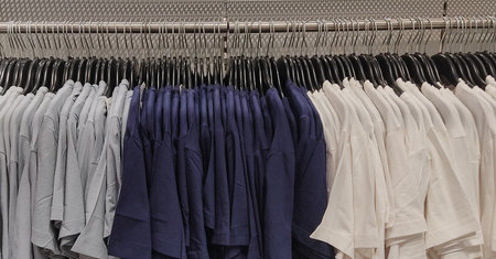 Greay Navy-blue white t-shirt in shop Unisex dresses on steel hangers in a retail shopの写真素材