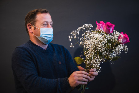 Happy caucasian florist making bouquets of red and pink roses for Valentine's day. Concept of human emotions, facial expression, love, and hard work in this pandemic times.の写真素材