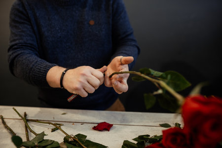 Happy caucasian florist making bouquets of red and pink roses for Valentine's day. Concept of human emotions, facial expression, love, and hard work in this pandemic times.の写真素材