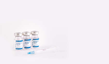 three Covid-19 vaccine vials with white background and a syringe to inject medical professionals and people at risk .. SARS-CoV-2 vaccination treatment. Copy space.の写真素材