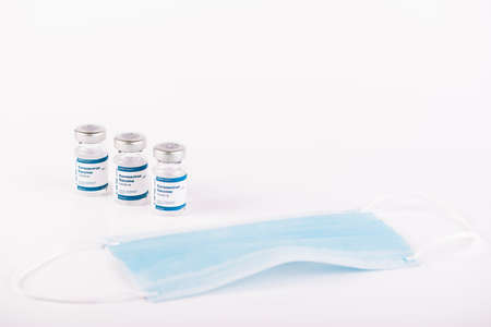 three Covid-19 vaccine vials with white background and a syringe to inject medical professionals and...