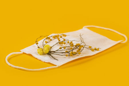 Close up of medicine face mask with yellow flowers and yellow background.