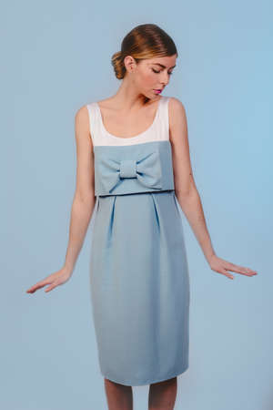 American shot of beautiful cheerful stylish fashion girl in blue dress looking down. Isolated on blue background. Design copy space.の写真素材