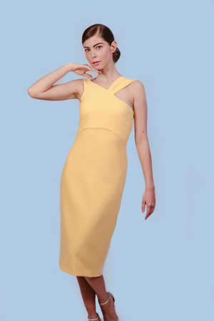 American shot of beautiful stylish blonde girl in yellow dress looking at camera. Isolated on blue background. Design copy space.の写真素材