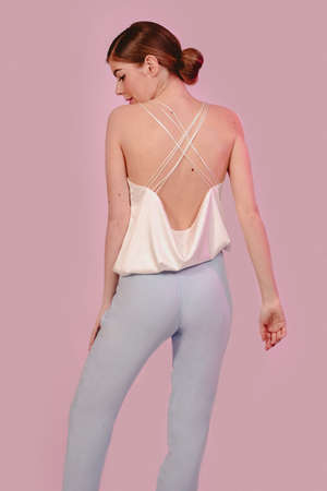American side view shot of beautiful stylish fashion girl in white and blue clothes looking at camera. Isolated on pink background. Design copy space.の写真素材