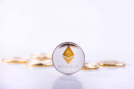 Crypto Currency Ethereum Coin Standing In Front Of Golden Bitcoins Laying On A Table On White Background. Ethereum Domination Concept. Cryptocurrency Stock Market Concept.の写真素材