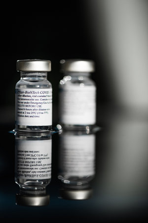San Sebastian, Gipuzkoa, Spain; 24 April 2021. Two Vials Of Pfizer-BioNTech Covid-19 Vaccine With Directions For Use. close up, selective focus. Blue light. Blue background.のeditorial素材