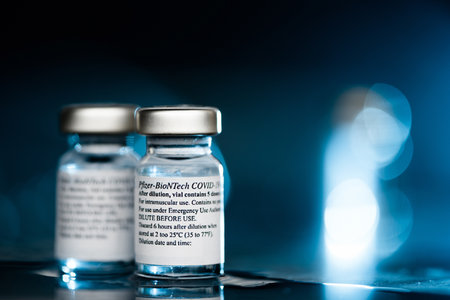 San Sebastian, Gipuzkoa, Spain; 24 April 2021. Two Vials Of Pfizer-BioNTech Covid-19 Vaccine With Directions For Use. close up, selective focus. Blue light. Blue background.のeditorial素材