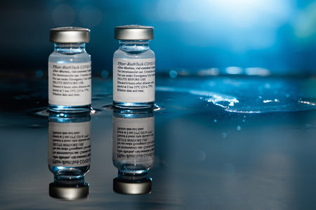 San Sebastian, Gipuzkoa, Spain; 24 April 2021. Two Vials Of Pfizer-BioNTech Covid-19 Vaccine With Directions For Use. close up, selective focus. Blue light. Blue background.のeditorial素材