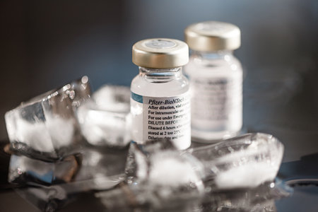 San Sebastian, Gipuzkoa, Spain; 24 April 2021. Two Vials Of Pfizer-BioNTech Covid-19 Vaccine With Directions For Use. close up, selective focus. Blue light. Blue background.のeditorial素材