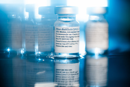 San Sebastian, Gipuzkoa, Spain; 24 April 2021. Two Vials Of Pfizer-BioNTech Covid-19 Vaccine With Directions For Use. close up, selective focus. Blue light. Blue background.のeditorial素材