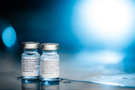 San Sebastian, Gipuzkoa, Spain; 24 April 2021. Two Vials Of Pfizer-BioNTech Covid-19 Vaccine With Directions For Use. close up, selective focus. Blue light. Blue background.のeditorial素材
