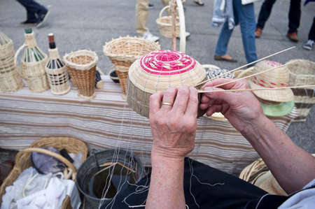 expert hands of the elderly craftsman creates a wicker basketの写真素材