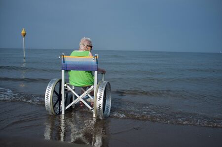 old woman from behind in a wheelchair at sea, aloneの写真素材