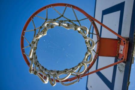 abandoned basketball basket, seen below, with a spider web in the middle