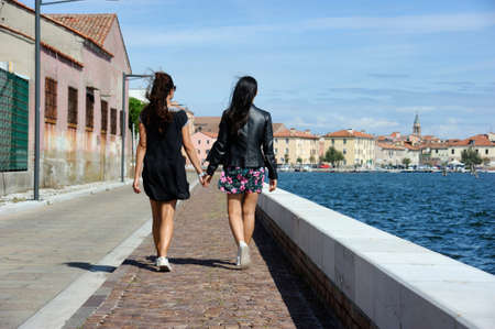 Loving couple of lesbian lovers, with hair blowing in the wind, shot from behindの写真素材