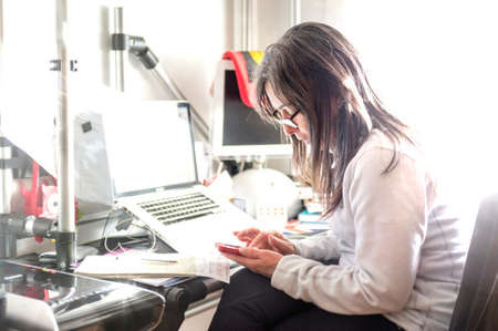caucasian lady, in home working office desk, with documents, laptop, smartphone, etc ...
