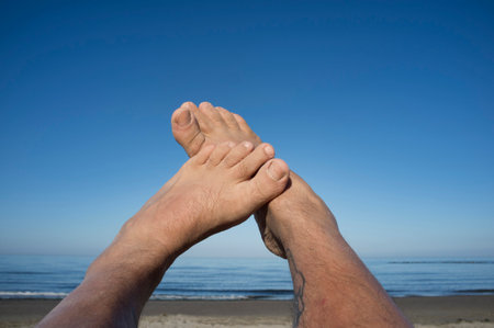 Leg and feet of a man under blue sky. Relaxing near the seeの写真素材