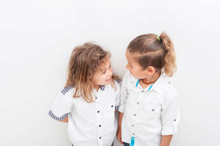 Two multiethnic boys brothers, with long blond hair look each other in the eyes