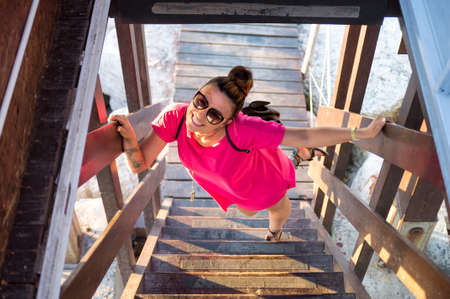 Attractive tattooed girl with sunglasses standing on the stairs and looking at the cameraの写真素材