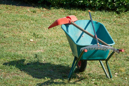 Gardening tools. Rake and garden shovel lying on wheelbarrow in the gardenの写真素材