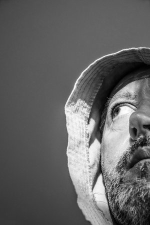gloomy middle-aged man with a gray beard with a bathrobe hood on his headの写真素材