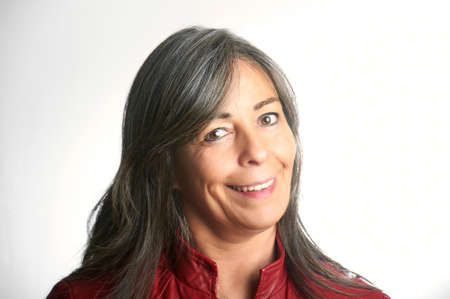 Close up portrait of a beautiful smiling older woman with gray hair and wearing a red jacket.