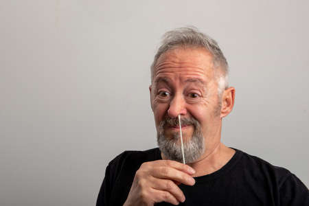middle aged man with gray hair and beard using the coronavirus (covid-19) antigen rapid self-test...