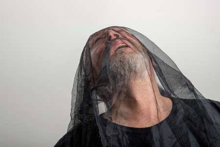 suffering man with a gray beard with a black veil on his head