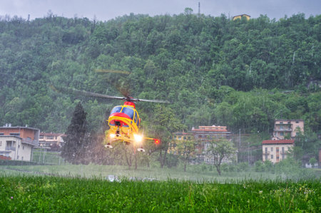Helicopter emergency medical service taking off from a hospital helipad in heavy rain during a...