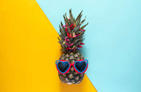 A smart pineapple in sun glasses and bright beads. Minimal concept, summer tropical pineapple. Summer, vacation, partyの写真素材