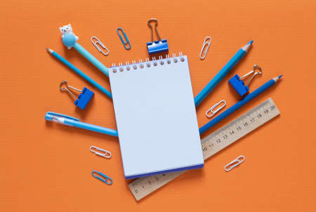 Back to school concept. School and office supplies on the office table. Orange background.Flat lay...