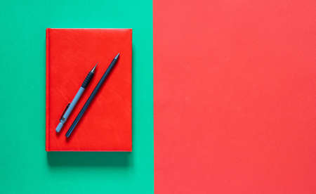 Back to school concept. Red notepad with pencils. Green and red background. Flat lay with copy...