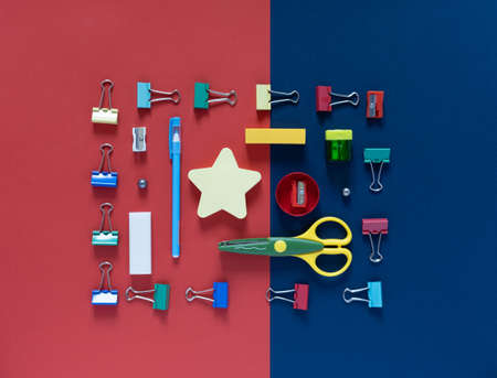 Back to school concept. School and office supplies on the office table. Blue and red background.Flat...