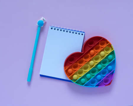 Back to school concept.Notepad, blue pen and antistress toy in the form of a heart on a pink background. View from above..Flat layの写真素材