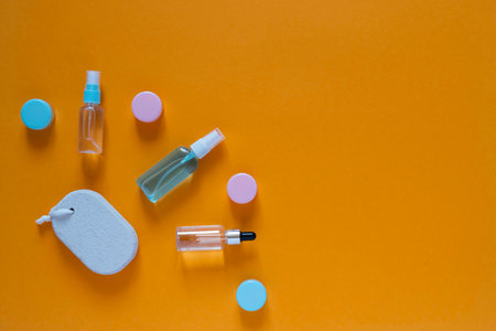 Flat composition with cosmetic products on an orange background. Multicolored sponges. Womens self-care. Top view image with copy space.の写真素材