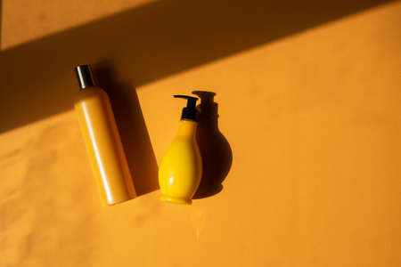 Mockup of yellow cosmetic bottles with shadow monstera leaves on yellow background. A creative, minimalistic shot of a cosmetic product. The concept of summer, natural cosmetics. Flat Lay.の写真素材