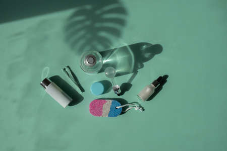 Body and spa treatments. Natural beauty products. Eco cream, serum, empty bottle for skin care. Glass pipette. Pumice stone for feet. Top view. Shadow from palm treeの写真素材