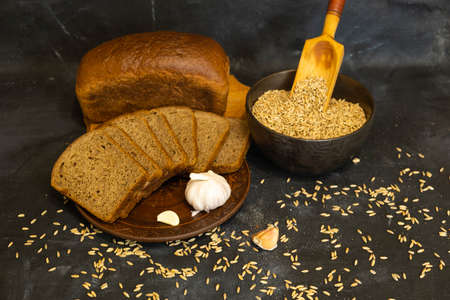 Rye bread on a dark background. Plate with grain